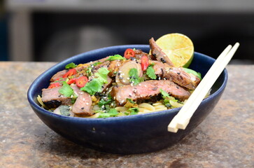 close up view of asian salad nam tok with noodles and beef