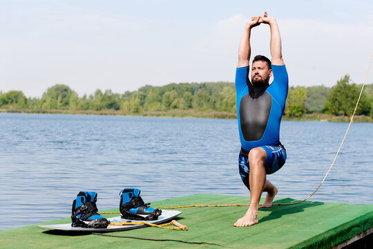 a wakeboarder is warming up next to a board with wakeboarding boots. warm-up before wakeboarding