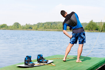 a wakeboarder warms up next to a board with wakeboarding boots