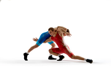 Fototapeta na wymiar Two strong and skilled wrestlers in blue and red wrestling uniform are wrestling and doing grapple against white studio background. Concept of fair wrestling, championship, win competition.