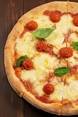 Pizza with tomato sauce, fresh mozzarella, Parmesan cheese and basil on wooden background.