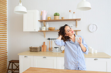 Young pretty woman drinking her morning coffee at kitchen