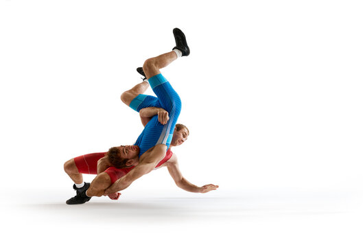Two young athlete man, skilled wrestlers in red and blue uniform fighting in motion against white studio background. Concept of sport, mixed martial arts, active lifestyle, movement.