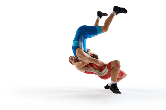Two athlete man wrestlers fighting in mid-action, one flipping other against white studio background. Concept of combat sport, mixed martial arts, active lifestyle, movement. Copy space. ad