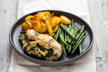 Roast potatoes and chicken stuffed with mozarella, spinach, pesto and sun dried tomatoes