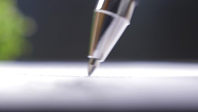 Ballpoint pen writes on a sheet of paper document, extreme close-up view
