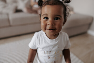 Portrait of joyful mixed race toddler girl in room. - obrazy, fototapety, plakaty