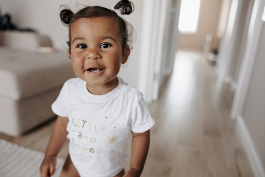 Portrait of joyful mixed race toddler girl in room.