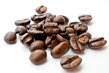 Naklejka premium A pile of coffee beans on a white surface.