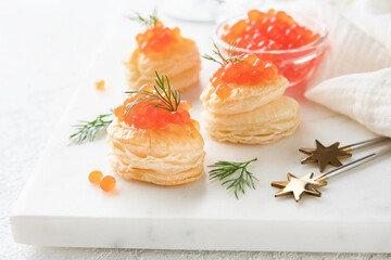 Salmon red caviar toast. Christmas canape or toast with red caviar on white plate on light...