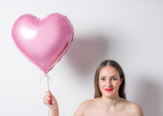 Obraz na płótnie Canvas Young pretty woman holding a heart shaped air balloon. Valentine's day concept.