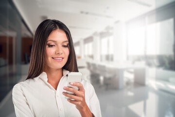 Young business woman with phone standing in office,