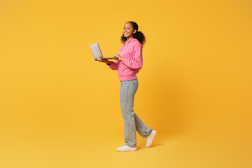 black student girl using laptop for education over yellow backdrop