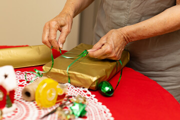 hands tying curling ribbon on gift wrapped in dull gold paper