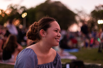 teen girl smiling at an outdoor concert at dusk
