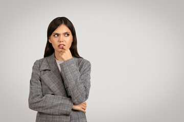 Woman in plaid blazer pondering, looking sideway at free space