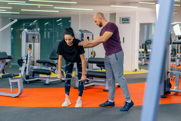 the girl does exercises with a barbell under the supervision of a trainer sport motivation support