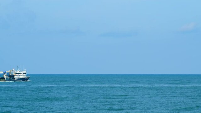Fishing Boat On The Horizon At Sea. Abstract Small Waves On Calm Water Surface In Motion. Real time.