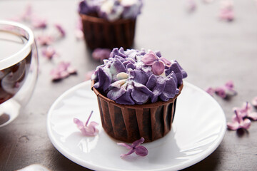 Floral purple cupcake close up using trend Dreamy Escapism. Desserts, coffee and lilac flowers...