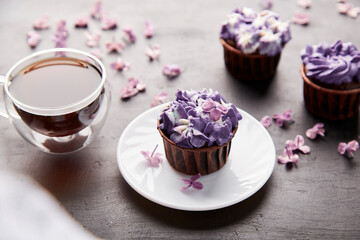 Aesthetics floral purple desserts using trend Dreamy Escapism. Cupcakes, coffee and lilac flowers background. No sugar food