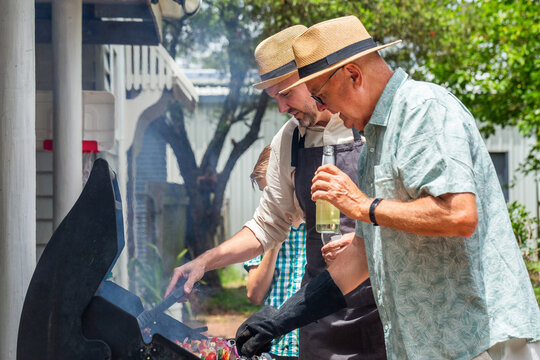 Man in his sixties drinking cider from bottle while standing by barbeque