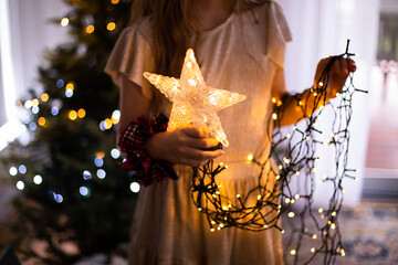 girl holding christmas tree star and strings of lights