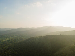 Aerial top view beautiful high mountains in the rays of the sun at sunset against a clear blue sky. Nature reserve, ecopark. Nature background. Photo from the drone.