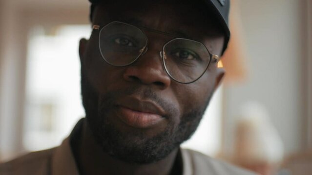 Face of an African American man looking at the camera, wearing glasses and a cap, close-up, handsome, confident lifestyle, slow motion.