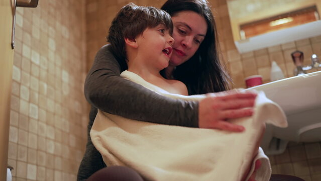 Nurturing scene of mother drying son after bath, bedtime night routine of nurturing mom taking care of her child seated inside bathroom. kid covered with towel receinv maternal affection