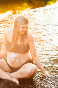Expectant First nations Australian woman sitting in water on country in NSW Australia