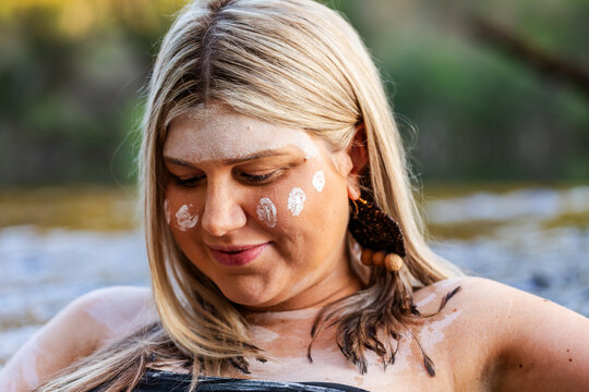 Aboriginal woman looking down in traditional ochre paint