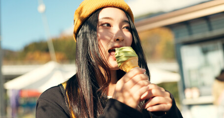 Japanese woman, ice cream and eating in city, summer and walk with thinking, memory or ideas on...