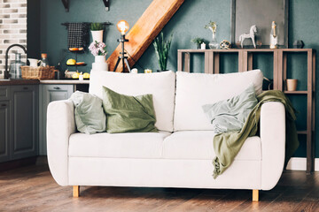 White sofa with green and grey velour cushions standing in american style modern kitchen interior