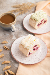 Roll biscuit cake with cream cheese and jam, cup of coffee on brown concrete, side view.