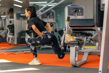 young girl in sportswear in the gym doing squats during fitness training healthy beautiful body