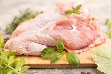 Raw turkey wing on a wooden cutting board on a brown concrete background. Side view, selective focus