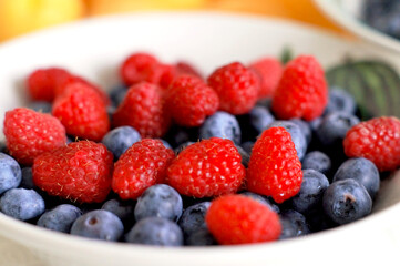 Healthy eating. Juicy raspberries and blueberries in a bowl