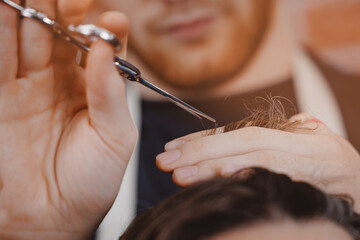 Obraz premium Barber shop, warm toning photo. Man in barbershop chair, hairdresser styling his long hair
