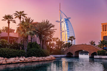 Dubai seaside skyline modern skyscraper luxury hotel on beach with palms, sunset light. Famous tourist landmark of UAE. - obrazy, fototapety, plakaty