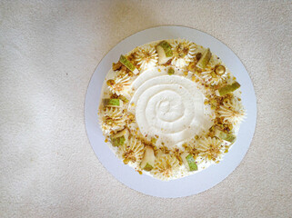 Layout white cake with white cream and slices of pear on a white plate on a light background