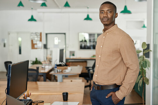Confident young African businessman standing alone in an office