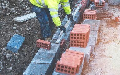 Hard working bricklayer laying concrete blocks on top of concrete foundation on new residential...