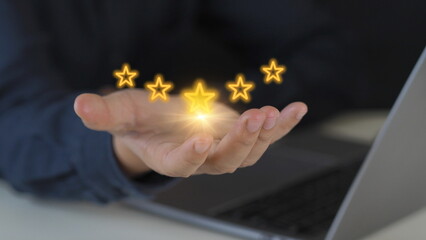 Businessman touches glowing yellow five-pointed star for excellent evaluation after customer uses ISO product service and global quality standards certification.