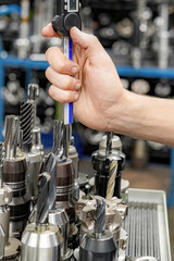 A worker in a tool warehouse inspects and selects cutters for work on a CNC milling and turning machine.