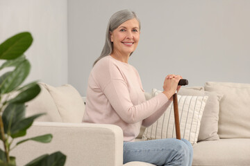 Mature woman with walking cane on sofa indoors