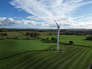 Aerial drone shot of an onshore wind turbine in the field on farmland in daytime