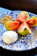 pomodori affettati crudi e mozzarella su piatto decorato con motivo blu, caprese italiana