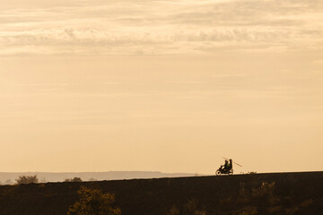 Silhouette of two men biker and a motorcycle on the road with sunset light background