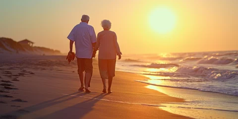 Fotobehang Strand zonsondergang A joyful elderly couple walking on the beach enjoying a leisurely sunset