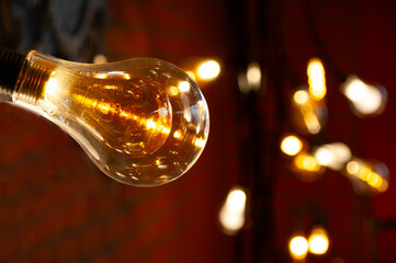 Transparent incandescent lamp on the background of a brick wall. Garland of lamps in a dark room.